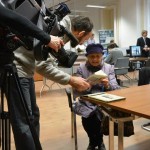 An elderly lady shows a reporter and news camera a letter from WW1
